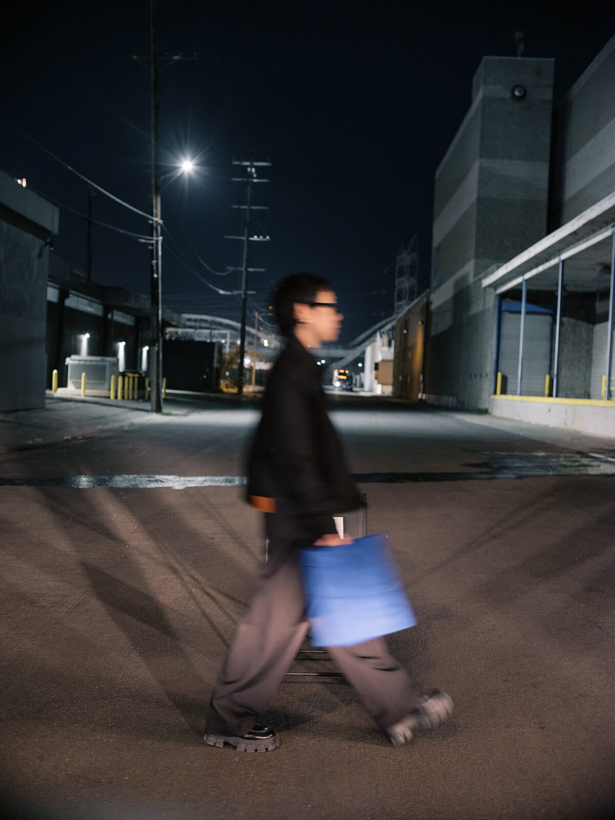 A motion-blurred figure carries a blue panel across the street mid-take